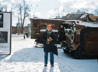 Olena, a Ukranian humanitarian worker poses in front of a snowy industrial background in Kharkiv